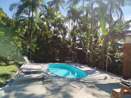 a swimming pool with a chair and a table and a chair at Sítio La Paz in Morretes