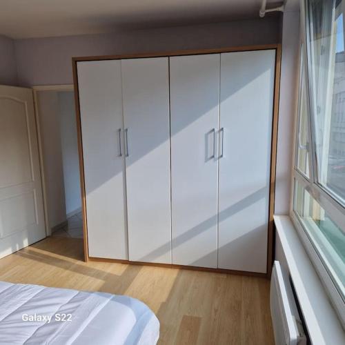 a bedroom with a large white closet with a window at Spacieux T3 lumineux avec balneo à 5min de la gare in Épinal