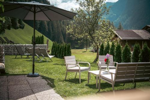 a group of chairs and an umbrella in the grass at Felda Appartements in Lappago