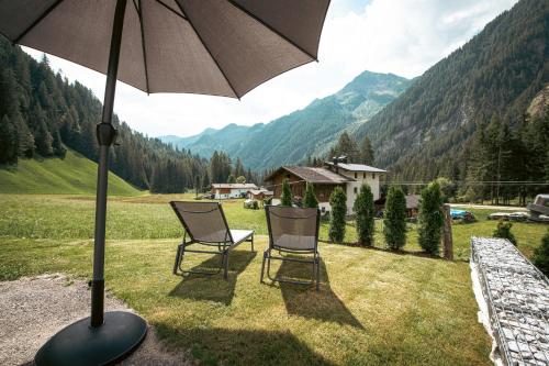 two chairs sitting under an umbrella in a field at Felda Appartements in Lappago