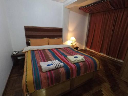 a bedroom with a bed with two towels on it at Apart House Happy CATA 001 in Puno