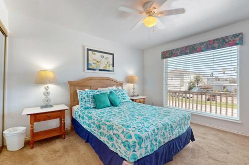 a bedroom with a bed with a ceiling fan and a window at Marlin Street Tomehome A in South Padre Island