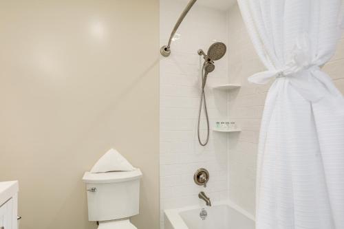 a white bathroom with a shower and a toilet at By Fort Pierce Inlet State Park! Condo with Yard in Fort Pierce