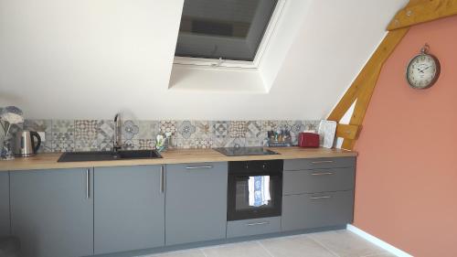a kitchen with a counter and a sink and a clock at La maison des Peupliers in Hoffen