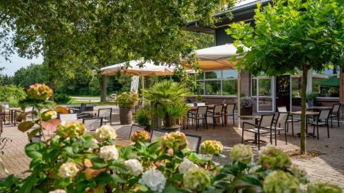 an outdoor patio with tables and chairs and flowers at Hotel Martensplek in Tiendeveen