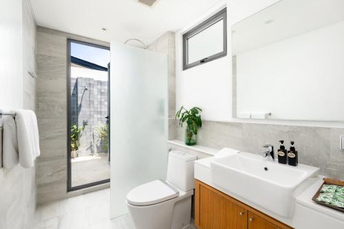 Twin Villas Natai - 7 Bedroom Luxury Beach Front Villa في شاطئ ناتاي: حمام مع مرحاض أبيض ومغسلة