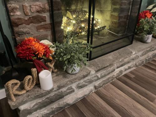 a fireplace with flowers and a candle on it at Peaceful Seasonal Wooded Cottage close to everything in Tafton