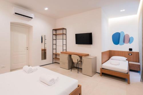 a room with two beds and a desk and a tv at Affittacamere Saint Bon 15 - 5 Terre Rooms and Suites in La Spezia