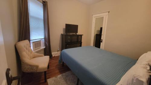 a bedroom with a bed and a chair and a window at Afrique Francaise de Woodlawn 1 in Chicago