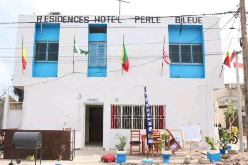 a white building with flags in front of it at Résidences Hôtel Perle Bleue in Cotonou