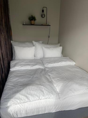 a large bed with white sheets and pillows at Modern apartment ONLY 5 minutes from City Centre in Bergen