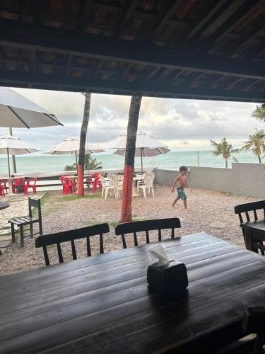 a boy walking on the beach near a table at Dom Aquino Hotel e Gastronomia in Natal