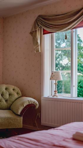 a bedroom with a bed and a window with a lamp at Svaneholm Hotel in Svanskog