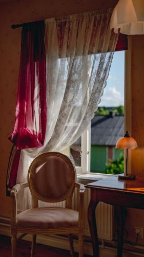 a chair sitting in front of a window with a table at Svaneholm Hotel in Svanskog