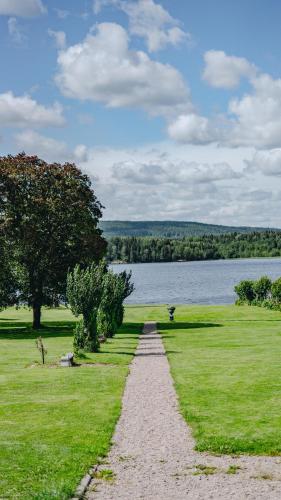 a path leading into a field next to a lake at Svaneholm Hotel in Svanskog