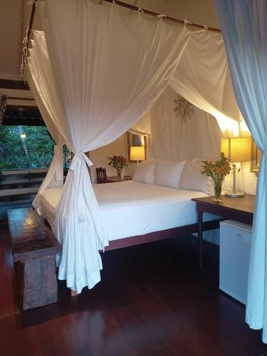 a bedroom with a large white bed with curtains at Monkey Casa Hotel in Trancoso