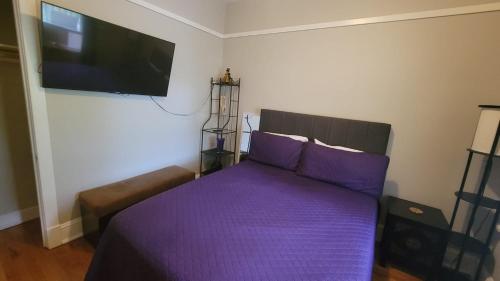 a bedroom with a bed with purple sheets and a flat screen tv at Afrique Francaise de Woodlawn 2 in Chicago