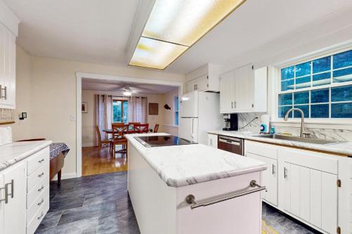 a kitchen with white cabinets and a large window at Tall Pines in Wellfleet