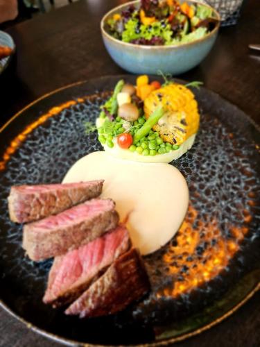 a plate of food with meat and vegetables on a table at Heerlijk Huys, Vakantievilla met privé tuin in Ewijk