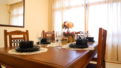 a wooden table with glasses and plates on it at Al Raha 3BR Retreat - Stylish Family Escape in Abu Dhabi