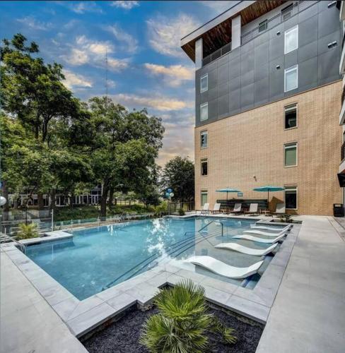 a swimming pool with lounge chairs in front of a building at Beautiful RiverWalk Apt with Full Amenities, King Bed & Free Parking in San Antonio