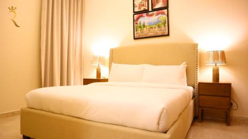 a bedroom with a white bed with two night stands and two lamps at Al Raha 3BR Retreat - Stylish Family Escape in Abu Dhabi