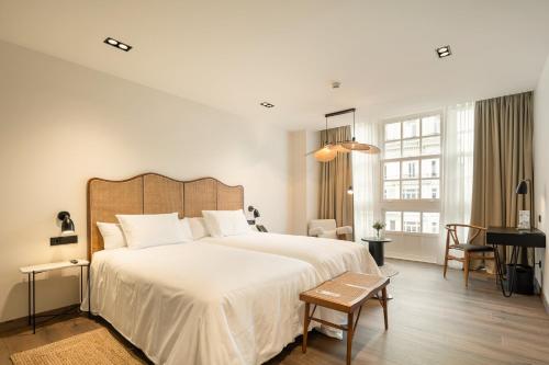 Un dormitorio con una gran cama blanca y un escritorio. en Sercotel EsteOeste, en Lugo