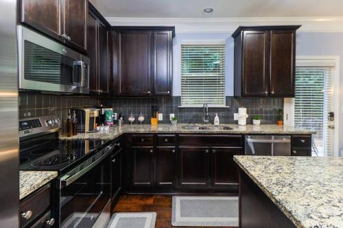 a kitchen with wooden cabinets and granite counter tops at Luxury Atlanta Home with King Bed and Yard in Lilburn