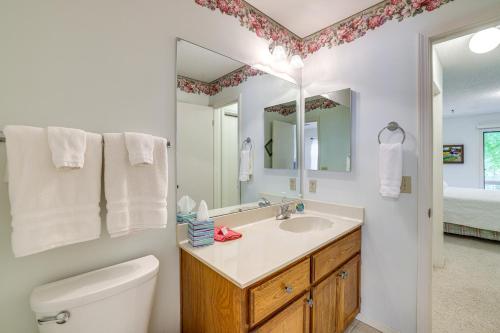 a bathroom with a sink and a toilet and a mirror at Bella Vista Townhome with Deck Near Back 40 Trail! in Bella Vista