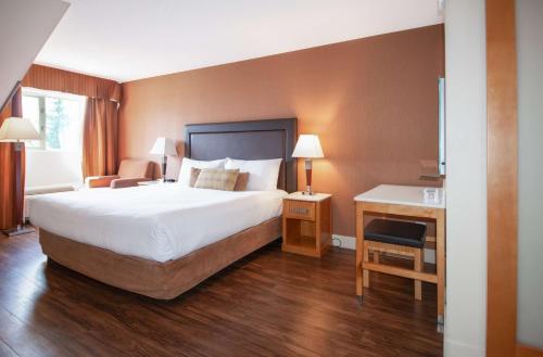 a hotel room with a large bed and a desk at Coast Hillcrest Hotel in Revelstoke