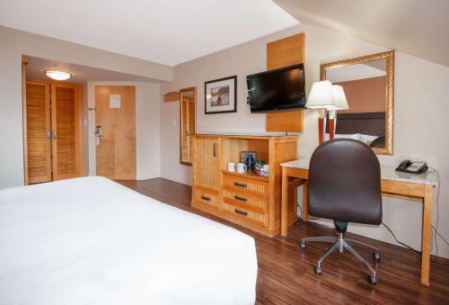 a hotel room with a bed and a desk and a mirror at Coast Hillcrest Hotel in Revelstoke