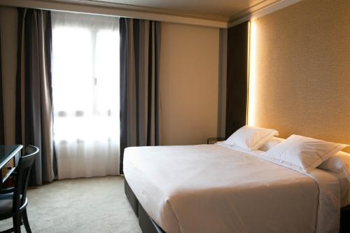 a hotel room with a large white bed and a window at Hotel Sercotel Ciudad de Oviedo in Oviedo