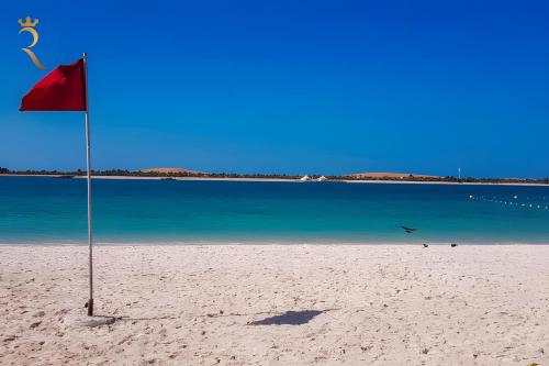 a red flag on a beach next to the water at Al Raha 3BR Retreat - Stylish Family Escape in Abu Dhabi
