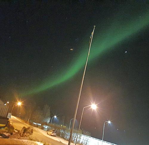 an aurora in the sky over a street with street lights at Eternus Paradise in Tärnaby