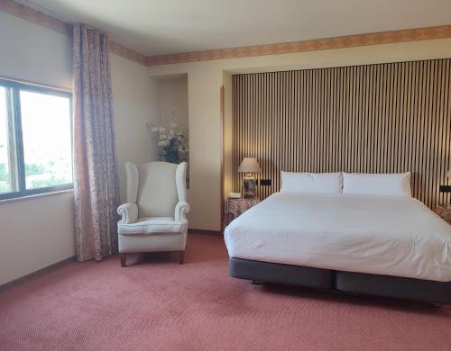 a bedroom with a bed and a chair and a window at Hotel Sercotel Cuatro Postes in Avila