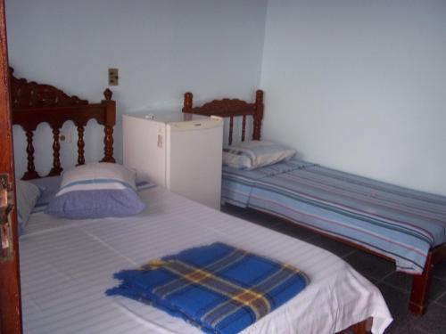 two twin beds in a room with a refrigerator at Pousada Riacho Doce in Caraguatatuba