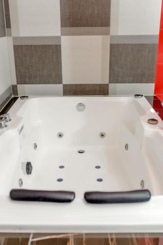 eine weiße Badewanne mit zwei schwarzen Griffen in der Unterkunft DURAZNO INN in Nuevo Casas Grandes
