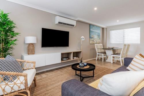 a living room with a couch and a tv at Marcoola Sands Retreat Steps from Marcoola Beach in Marcoola