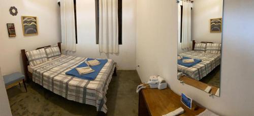 a room with two beds and a table and a mirror at Pousada Caminho do Vale Guiné in Mucugê