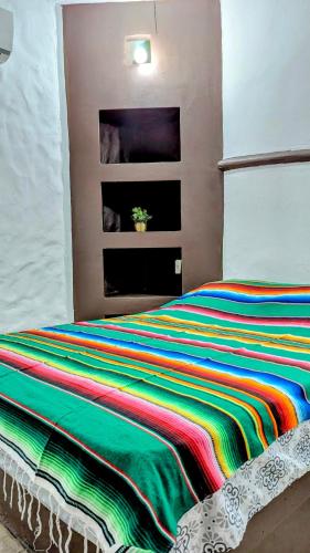 a bed with a colorful blanket on it in a room at Hotel Casa de Arnold in Mazatlán