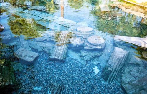 a reflection of a pond with rocks in the water at Gökçen Home in Pamukkale