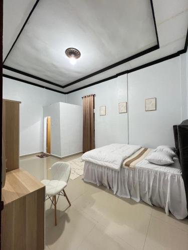 a white bedroom with a bed and a chair at Acc Family Homestay in Takengon