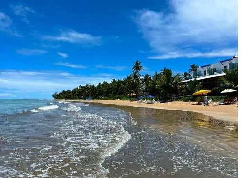una spiaggia con sedie e ombrelloni e l'oceano di Casa Aconchego do Mar a Japaratinga