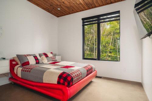 Saint-FaustinLoft Exécutif CherLieu de luxe avec vue sur golf et montagnes的带红色床和窗户的卧室