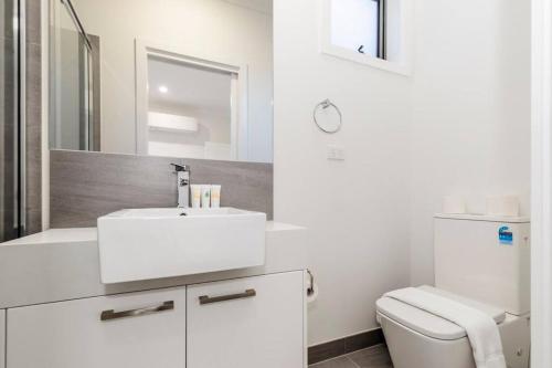 a white bathroom with a sink and a toilet at 4 Bedrooms Lovely House in Clayton Central in Clayton North