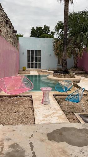 a pool with pink and blue tables and a palm tree at Casa de los Gatos in Mérida