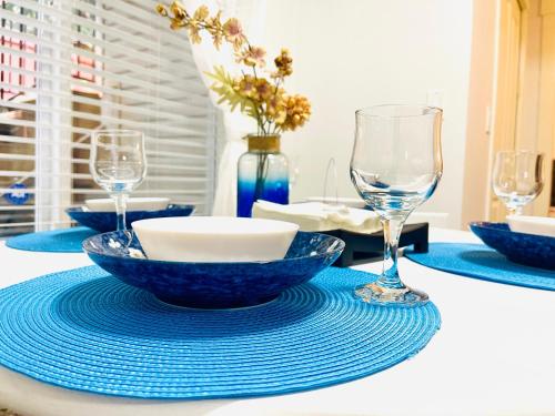 a table with blue bowls and wine glasses on it at Langley Heights 2 Bedrooms Sweet Suite in Langley