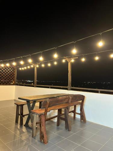 une table et un banc en bois sur un toit avec des lumières dans l'établissement Nhã Hotel, à Phan Rang