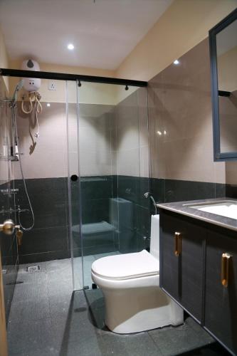 a bathroom with a toilet and a glass shower at Lumis studio apartment in Hyderabad