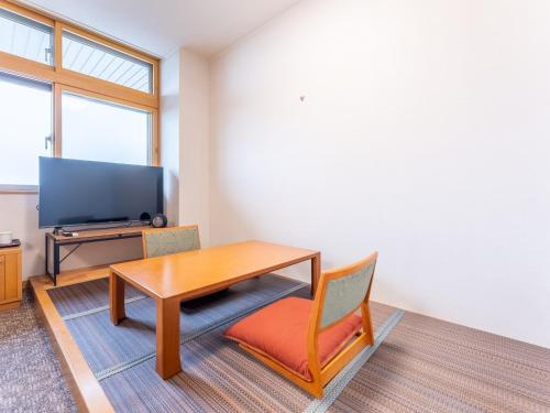 a room with a table and a chair and a television at LiVEMAX Resort Upopoi Shiraoi Onsen in Shiraoi